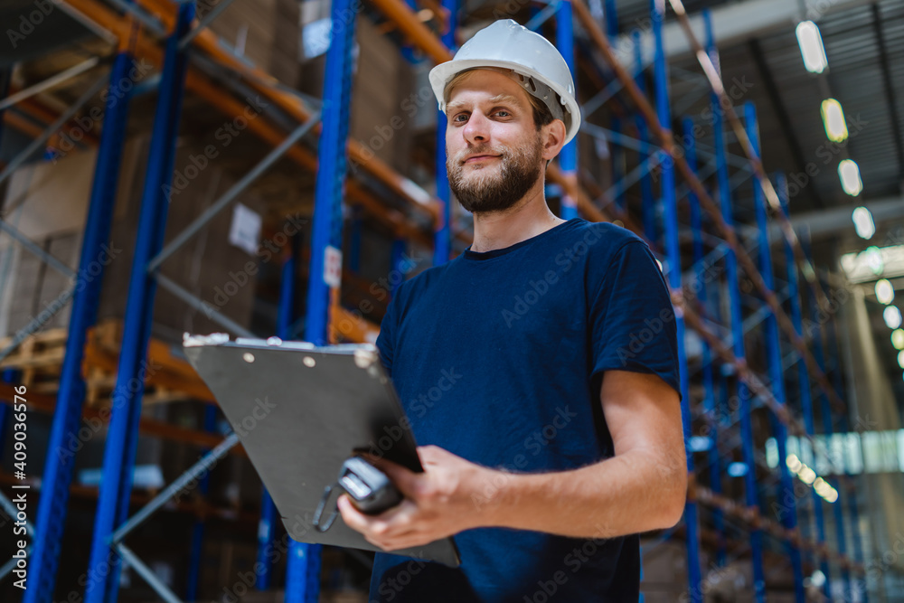 young warehouse manager checking goods using a clipboard in a warehouse young warehouse manager checking goods using a clipboard in a warehouse