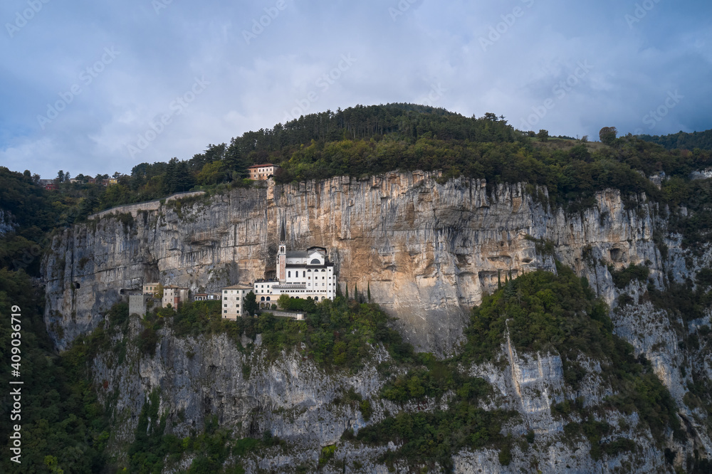 Aerial view of the church on the sheer cliff. The unique Sanctuary Madonna della Corona church was built in the rock. Italian church in the Alps. The sanctuary is high in the mountains of Italy.