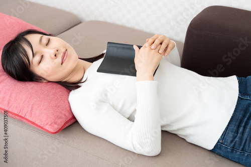 Woman sleeping while reading a book on the sofa