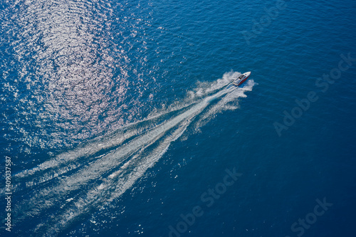 Boat in the sun. Aerial view of a boat in motion on blue water. Top view of a white boat sailing in the blue sea. luxury motor boat. Drone view of a boat sailing at high speed.