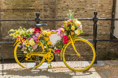 Yellow bicycle decorated with flowers at the canal in Gouda, Netherlands photo