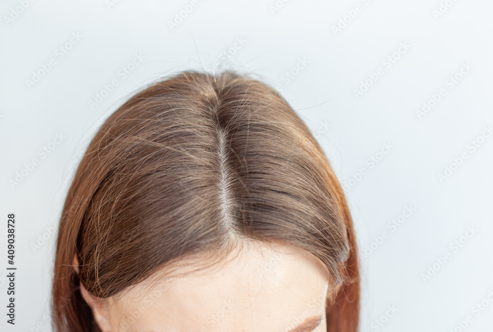 A woman's head with a parting of gray hair. A woman's head with a parting of gray hair.