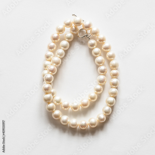 folded natural white pearl necklace on white background
