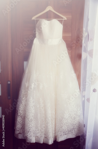 The bride's white wedding dress hangs on the wardrobe