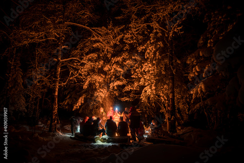 People in the winter night forest around a campfire