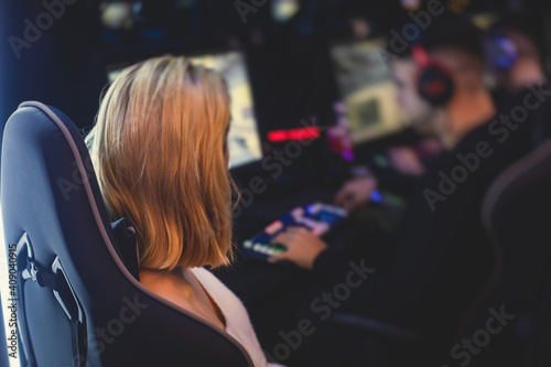 Female gamer, cyber sport e-sports tournament, professional girl gamers, close-up on gamer's hands on a keyboard, pushing button, in a cyber games arena club, girls playing and streaming fps game