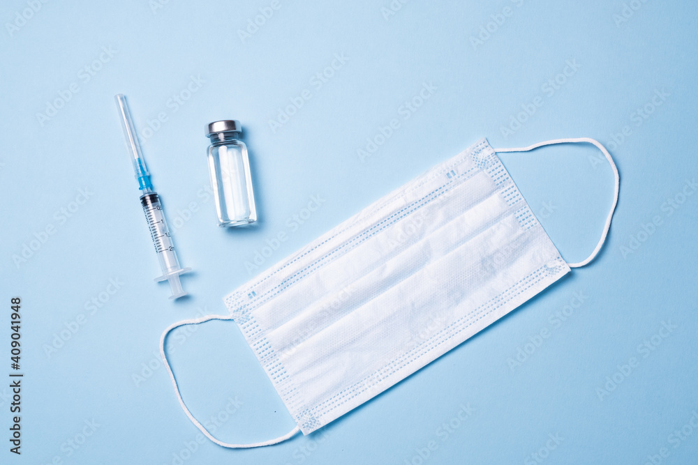 Vials with vaccine, syringe and mask on blue background, flat lay. Space for text. The concept of protection against coronavirus infection, COVID-19, vaccination. Banner Vials with vaccine, syringe and mask on blue background, flat lay. Space for text. The concept of protection against coronavirus infection, COVID-19, vaccination. Banner
