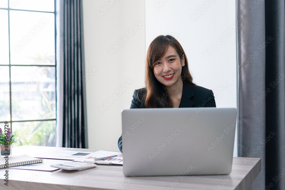 Asian female finance worker working on a laptop At home office table, sit at work with happiness and smile, work from home ideas. Asian female finance worker working on a laptop At home office table, sit at work with happiness and smile, work from home ideas.