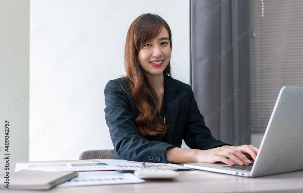 Asian female finance worker working on a laptop At home office table, sit at work with happiness and smile, work from home ideas. Asian female finance worker working on a laptop At home office table, sit at work with happiness and smile, work from home ideas.