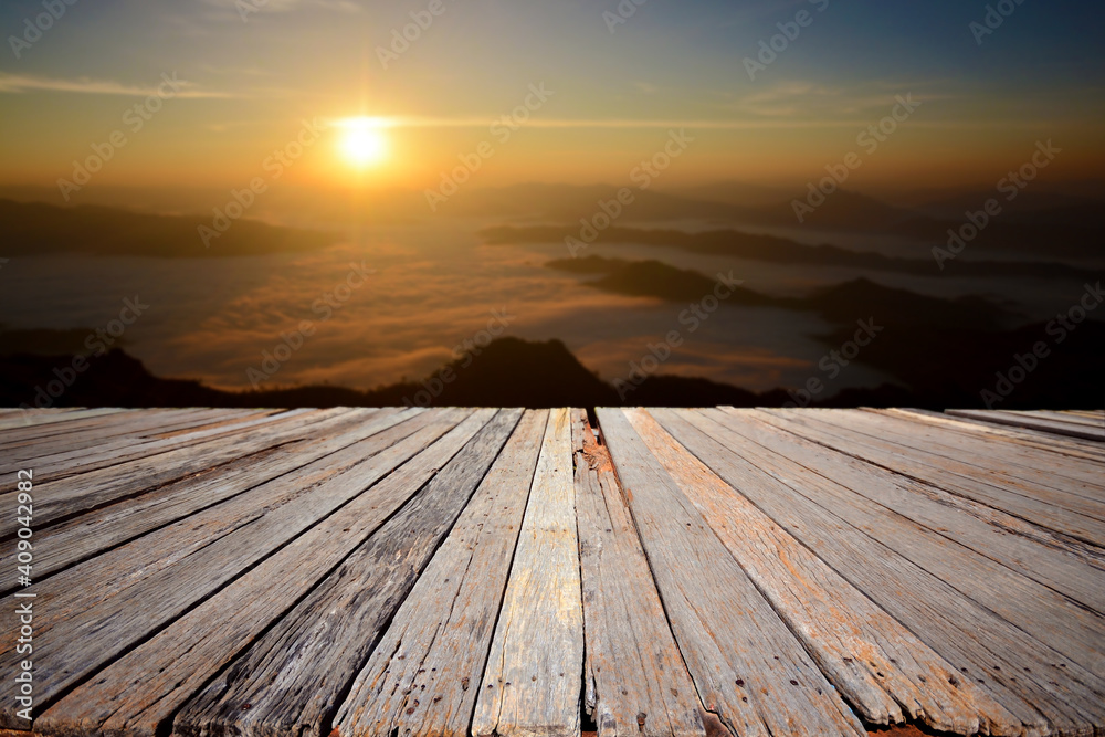 An empty wooden terrace with mountain view and mist during sunrise. An empty wooden terrace with mountain view and mist during sunrise.