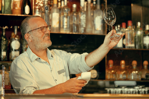 The bartender wipes out the wine glass at work. photo