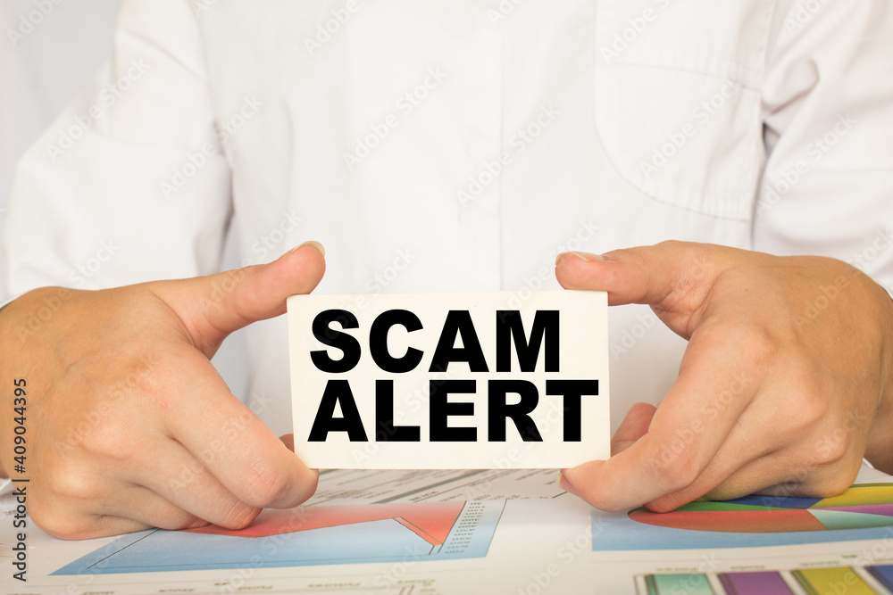 a man in the office holds a card with text SCAM ALERT . business concept a man in the office holds a card with text SCAM ALERT . business concept