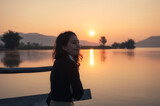 Beautiful young asian woman enjoying with sunrise on mountain lake