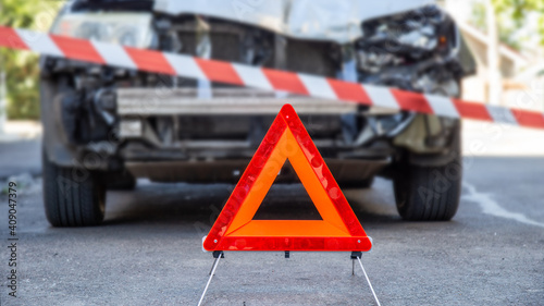 Obraz na plátně Destroyed car in car crash traffic accident on city road with Police tape and Red emergency stop triangle sign