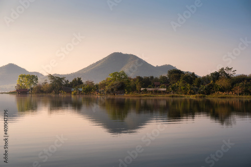 Scenery of mountain with traditional village floating on Lam Taphoen reservoir in the morning