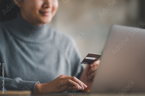 online shopping concepts, woman hands using laptop computer for online shopping at home, Hand holding credit card and Payment Detail page on computer.