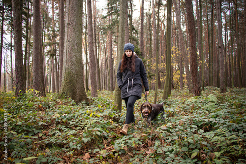 walk through the woods of young brunette aged 20-24 with her female Rough-coated Bohemian Pointer. Dominance of love, relationship and devotion to the lord. Candid portrait in sail set champagne tone