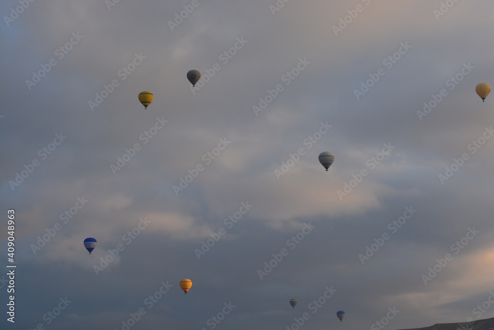 Tourist hot air balloons floating in the cloudy sky in Cappadocia. Cloudy weather. Colorful balloons. Tourist hot air balloons floating in the cloudy sky in Cappadocia. Cloudy weather. Colorful balloons.