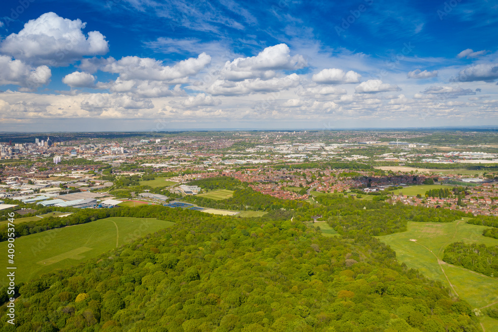 Aerial photo of the city of Leeds viewed from the village of Middleton and Middleton Park on a sunny day with white clouds in the sky and a lot of green trees in the summer time