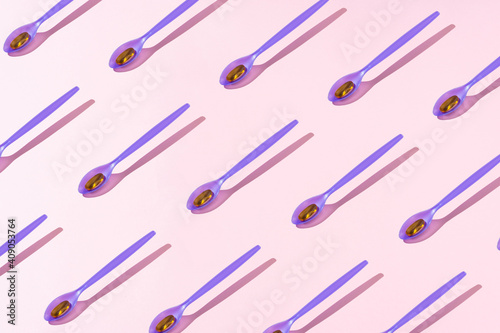 Creative pattern fish oil tablet on purple plastic spoon. 
