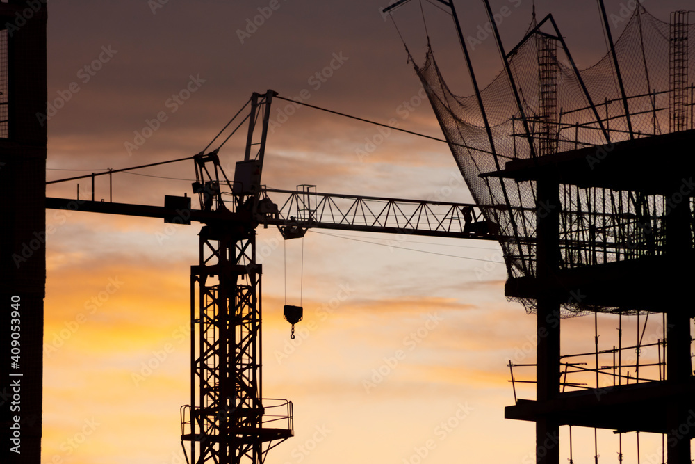 Silhouette of a crane and a building with net