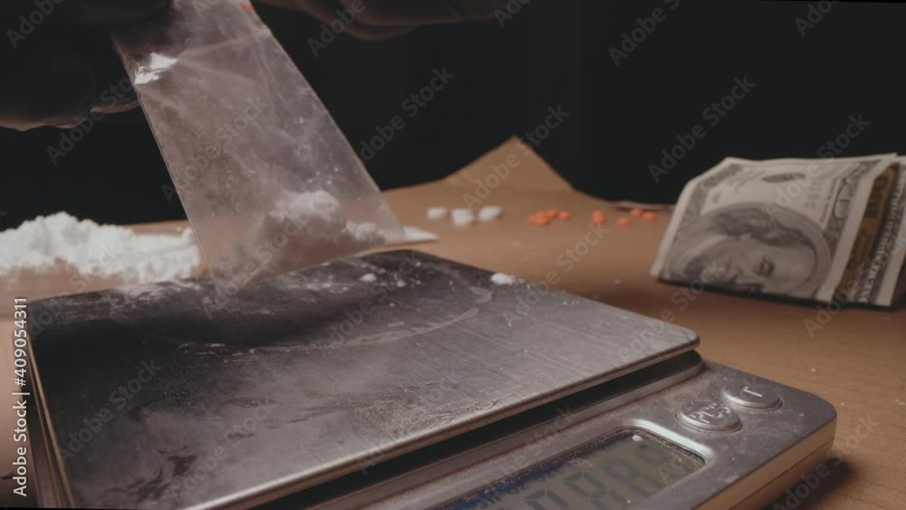 Drug dealer packing and weighing white powder, cocaine or heroin. Drug dealer packing and weighing white powder, cocaine or heroin.