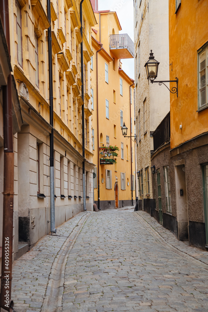 Cobbled street in a small town in Sweden. Yellow houses on a narrow street in Sweden. Swedish architecture. 