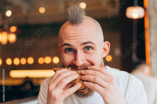 A brutal man of European appearance in a cafe has a delicious sandwich