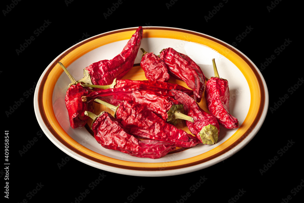 Red dried chili peppers in a round plate. Heap of hot dry peppers on a black background. Red dried chili peppers in a round plate. Heap of hot dry peppers on a black background.