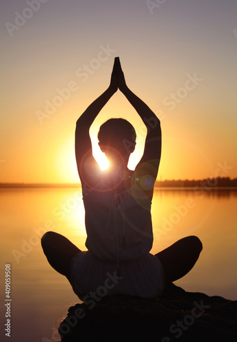Fototapeta Naklejka Na Ścianę i Meble -  Woman practicing yoga near river on sunset. Healing concept