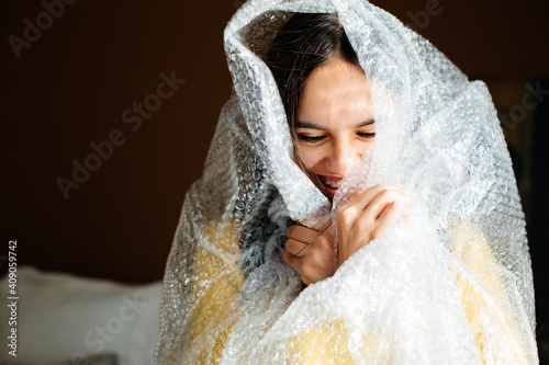 Photography Laughing teen girl with braces wrapped in bubble wrap hiding and popping bubbles