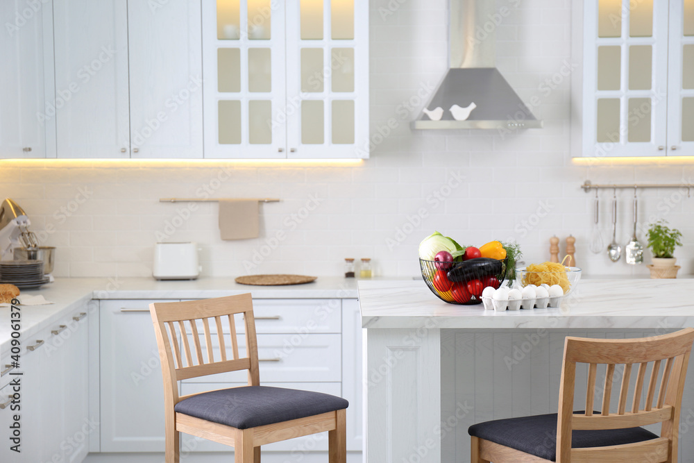Modern kitchen interior with different products on white table Modern kitchen interior with different products on white table