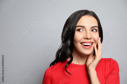 Portrait of surprised woman on grey background, space for text