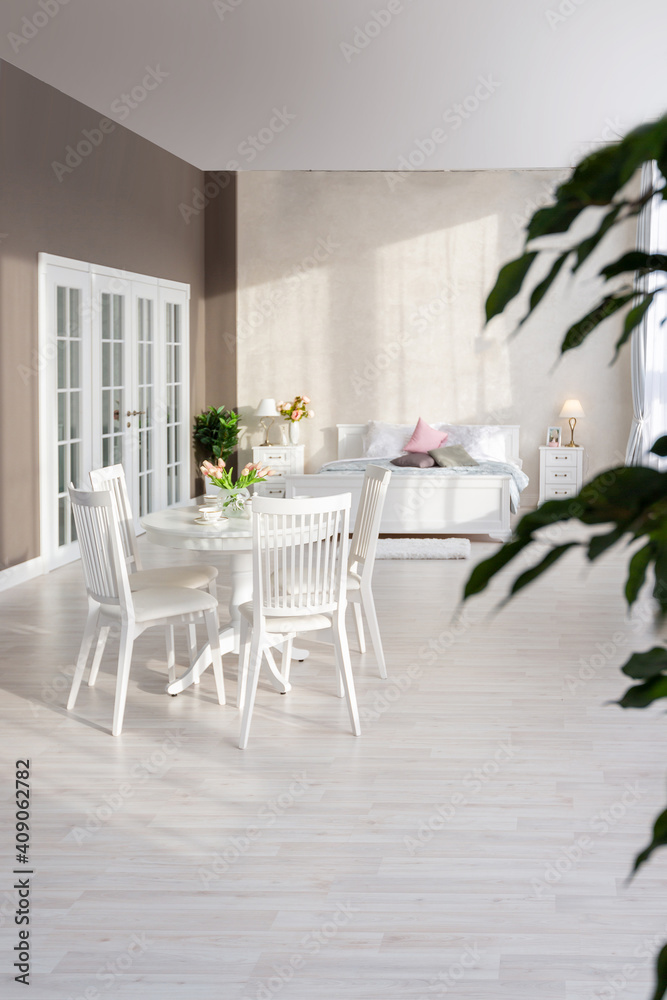 Fototapeta premium Luxurious and expensive interior of an open-plan apartment in light colors. Stylish modern bedroom with minimal design, dining area and guest space.