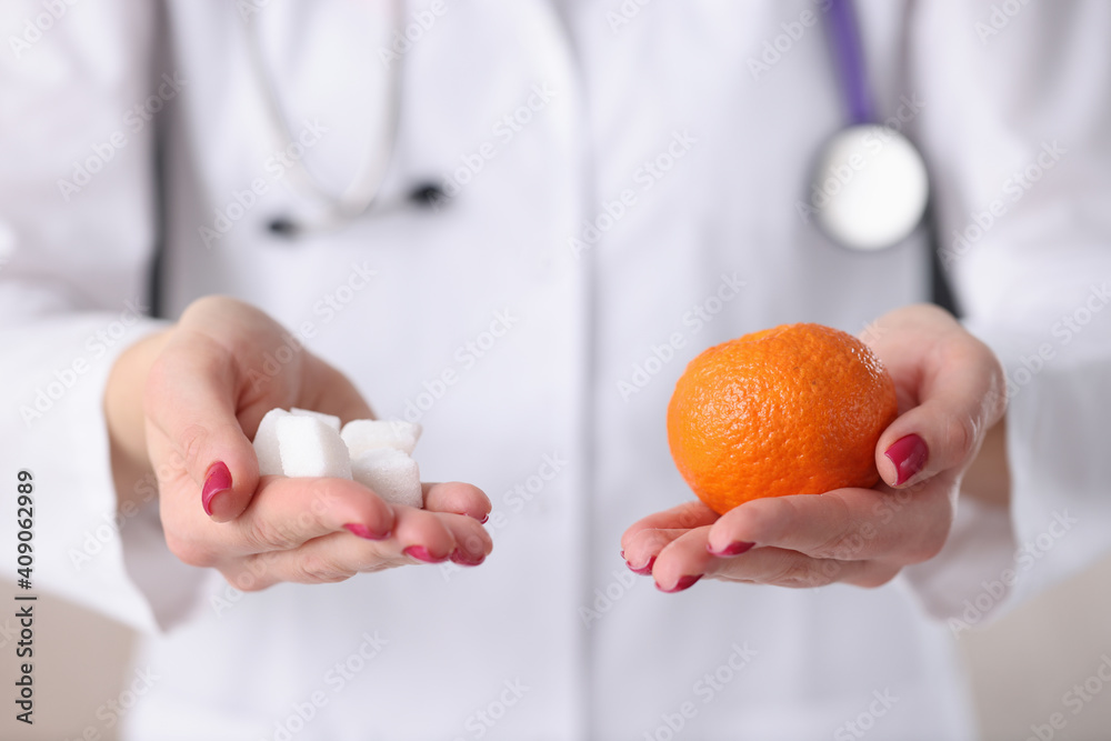 Doctor holding orange and sugar cubes in his hands closeup