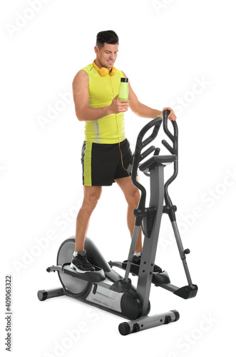 Man with bottle on modern elliptical machine against white background