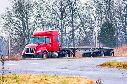 Photography An Empty Flatbed Tractor Trailer Drives in Mixed Winter Weather