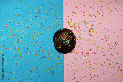 Brown muffin on the blue-pink background with sprinkles. photo