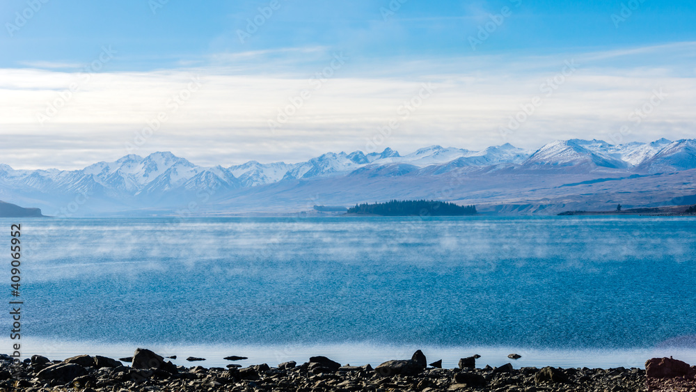 A foggy winter day at the Lake Tekapo on New Zealand‘s South Island, snow capped mountains, the Southern Alps, in the distance 