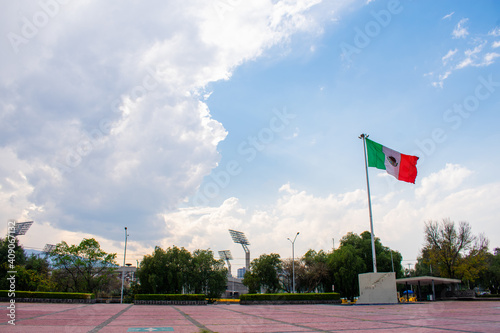 Wavy Mexican flag in public square with a cloudy sky as background photo