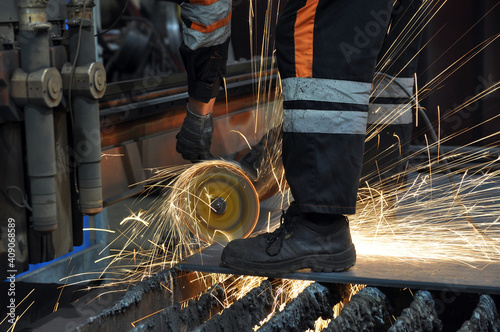 Worker at the factory cuts metal. sparks.