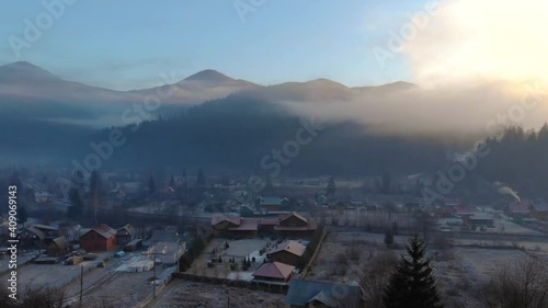 Mountain Village in the Morning. Aerial Shot of Majestic Sunrise in a Valley at Foggy Morning Mountains Landscape. Fir Tops and Cozy Houses in Carpathians, Tatariv, Ukraine, Europe photo