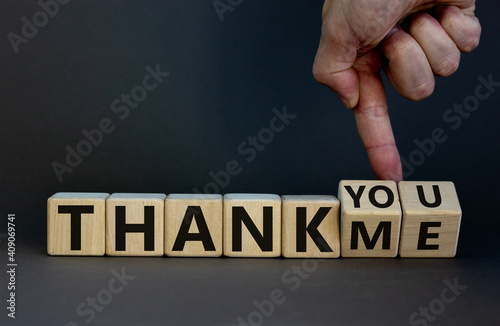 Thank you or me symbol. Businessman turns cubes and changes words 'thank me' to 'thank you'. Beautiful grey background, copy space. Business, psychology and thank you or me concept.