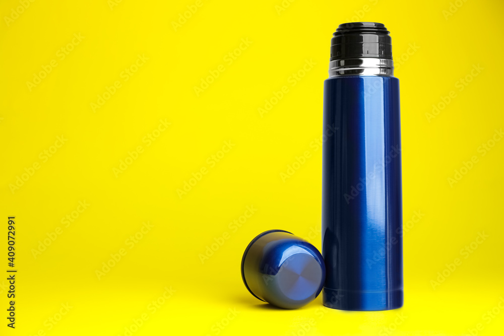 Stylish thermo bottle on yellow background, space for text Stylish thermo bottle on yellow background, space for text