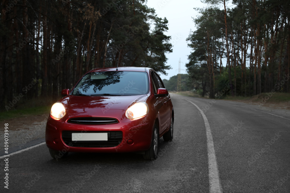 Red car on highway near wood. Road trip Red car on highway near wood. Road trip