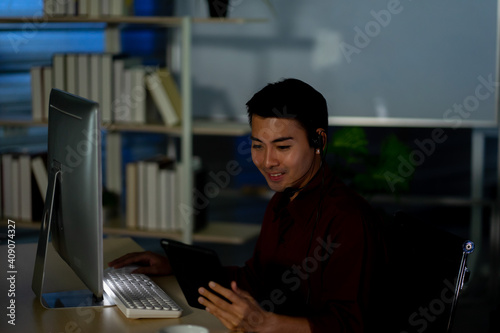 Asian business employee working in call center customer service office in the night 