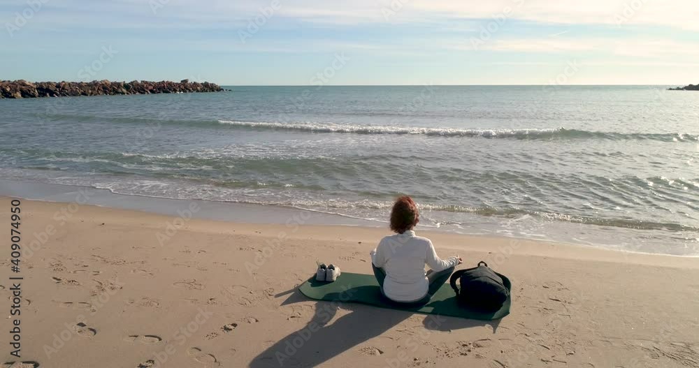 Vista de espalda con dron de mujer de mediana edad sentada reflexionando delante del sol