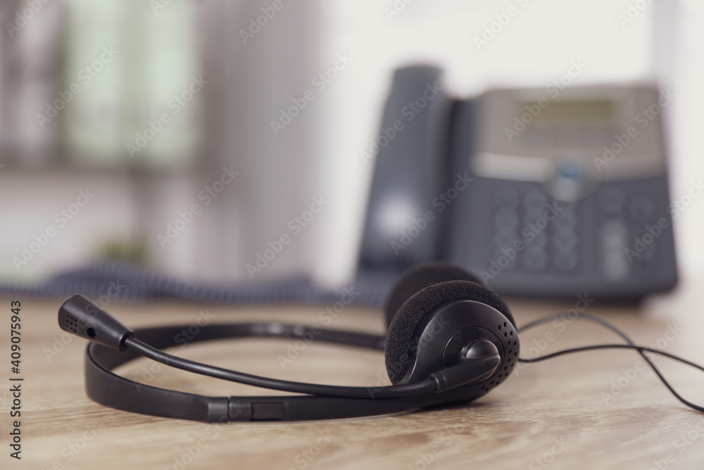 Headset on wooden table in office, closeup with space for text. Hotline service Headset on wooden table in office, closeup with space for text. Hotline service