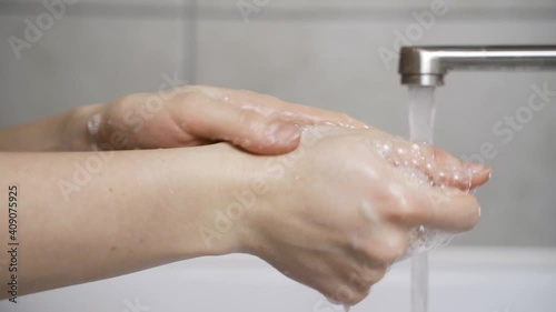 woman washing her hands properly with plenty of soap in her home sink without wasting water photo