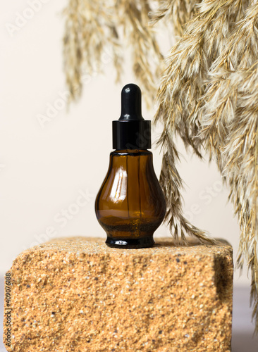A brown bottle of cosmetic products on the stone. Essential natural oil in a brown bottle on a stone. Natural organic spa cosmetic beauty concept